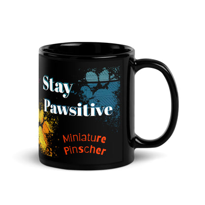 Stay Pawsitive text with image of a Miniature Pinscher dog on stained glass style background with colorful paw prints on a black ceramic mug 11 oz — handle on right