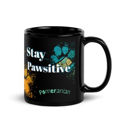 Stay Pawsitive text with image of a Pomeranian dog on stained glass style background with colorful paw prints on a black ceramic mug 11 oz — handle on right