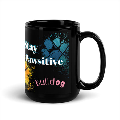 Stay Pawsitive text with image of a Bulldog on stained glass style background with colorful  paw prints on a black ceramic mug 15 oz — handle on right