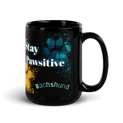 Stay Pawsitive text with image of a Dachshund dog on stained glass style background with colorful  paw prints on a black ceramic mug 15 oz — handle on right